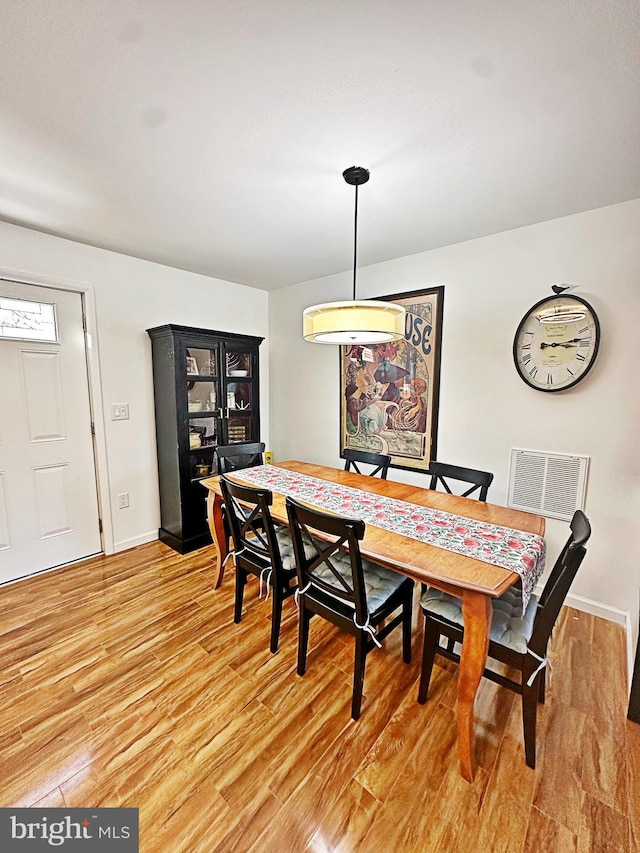 dining space with light wood-type flooring, baseboards, and visible vents