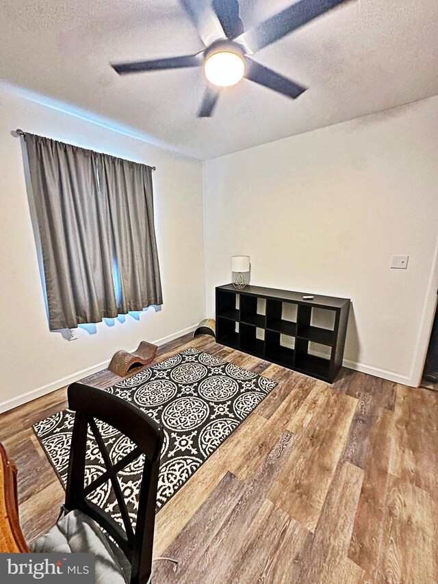 bedroom featuring a textured ceiling, ceiling fan, wood finished floors, and baseboards