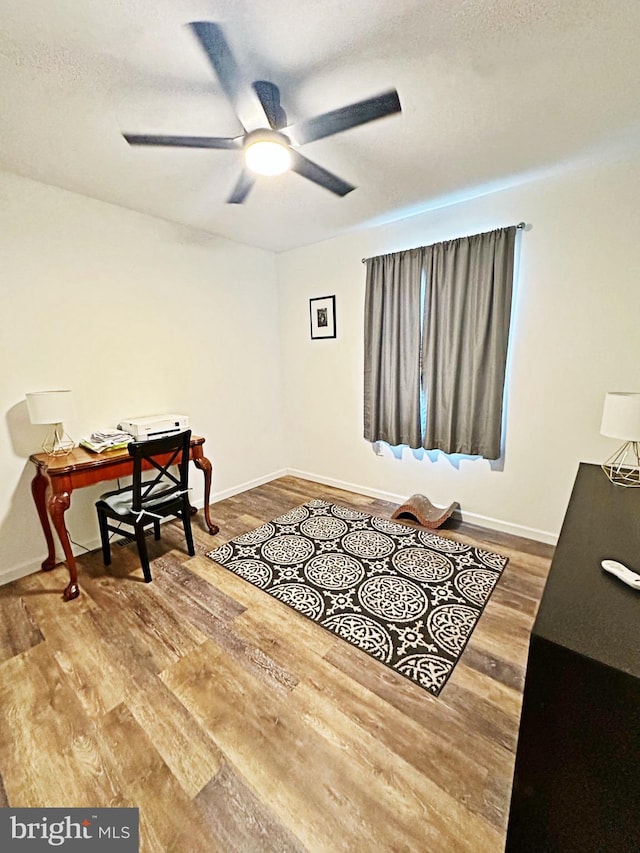 sitting room with ceiling fan, baseboards, and wood finished floors