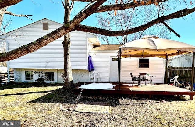 back of property featuring fence, a deck, and a gazebo