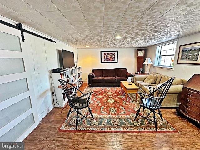 living room with a barn door and wood finished floors