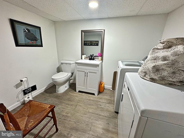 laundry area with laundry area, baseboards, light wood-type flooring, washing machine and dryer, and a sink