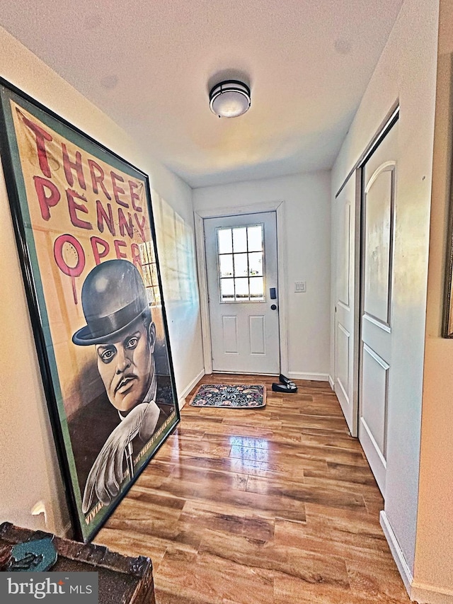 entryway with a textured ceiling, baseboards, and wood finished floors