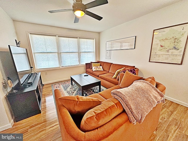 living room featuring baseboards, ceiling fan, and light wood-style floors