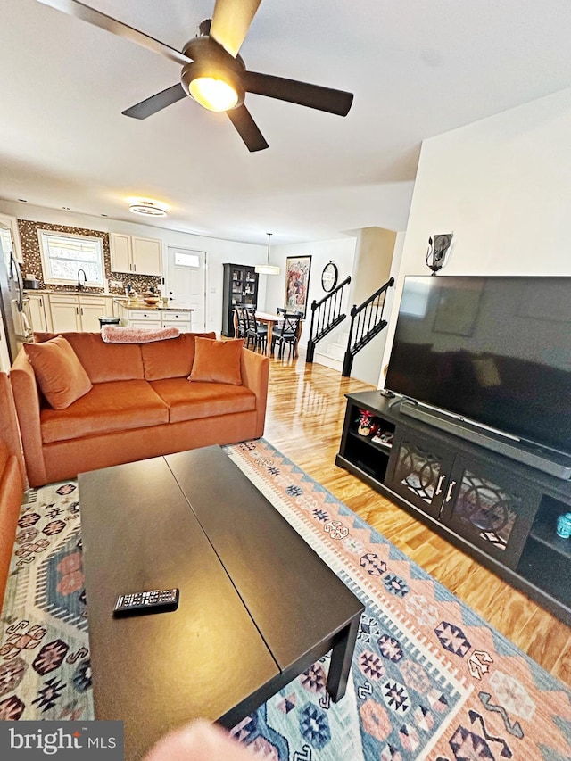 living area with stairs, ceiling fan, and wood finished floors