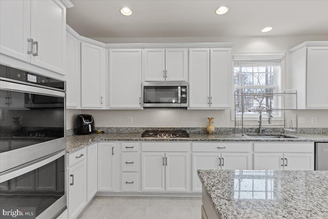 kitchen featuring stainless steel appliances, white cabinetry, and sink