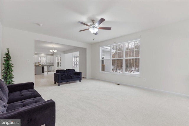 living room with light carpet and ceiling fan with notable chandelier