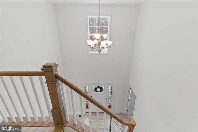 stairway featuring a notable chandelier