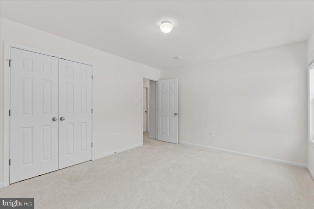 unfurnished bedroom with light carpet and a closet