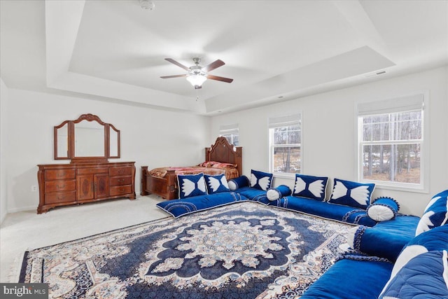 bedroom featuring ceiling fan, a tray ceiling, and carpet flooring