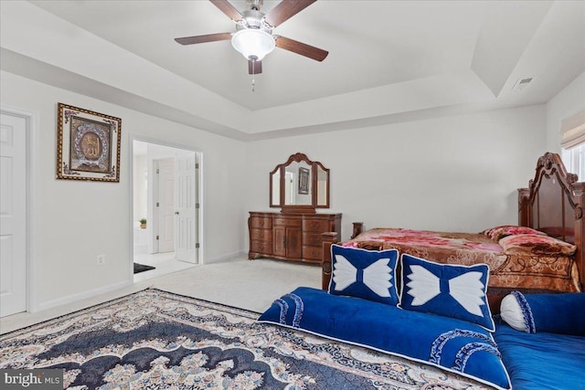 carpeted bedroom featuring ceiling fan and a raised ceiling