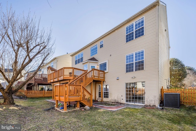 rear view of property with a wooden deck, central AC unit, and a lawn