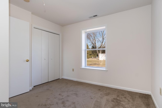 unfurnished bedroom with light colored carpet and a closet