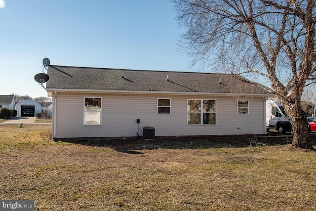 back of house featuring central AC unit and a lawn