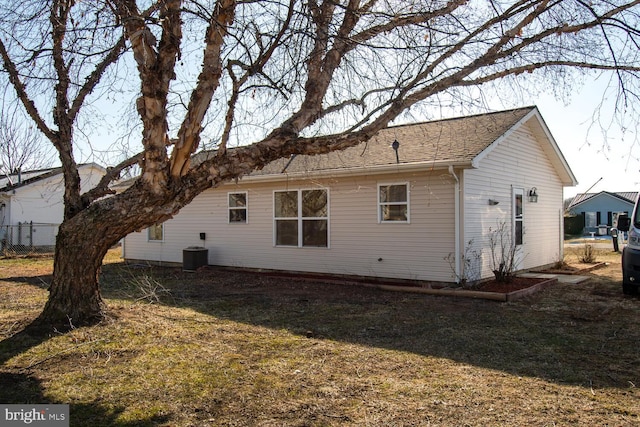 rear view of house featuring cooling unit and a lawn