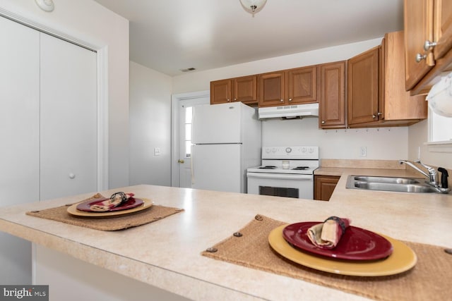 kitchen with white appliances, kitchen peninsula, and sink