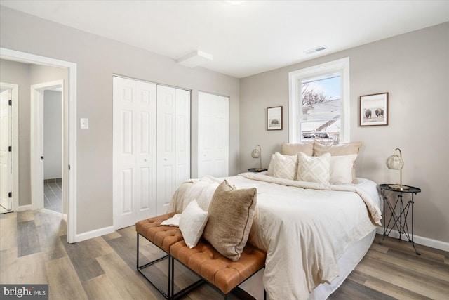 bedroom with multiple closets and hardwood / wood-style flooring