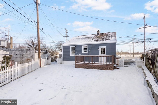 snow covered house with a wooden deck