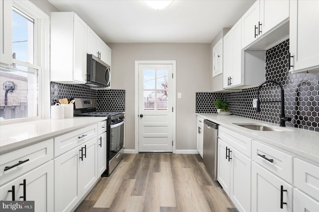 kitchen featuring a wealth of natural light, white cabinets, appliances with stainless steel finishes, and sink