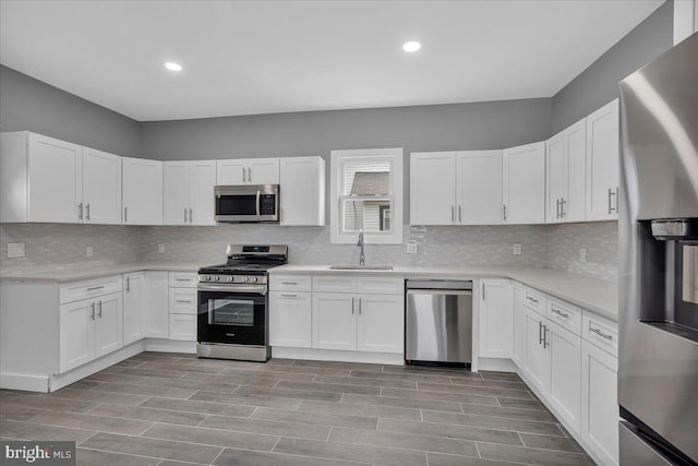 kitchen featuring decorative backsplash, sink, stainless steel appliances, and white cabinetry