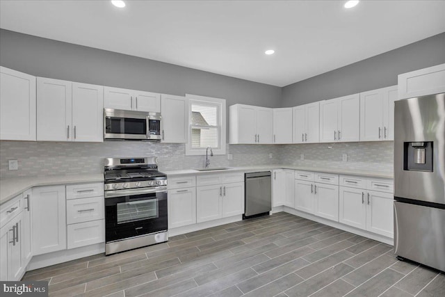 kitchen with appliances with stainless steel finishes, decorative backsplash, white cabinets, and sink