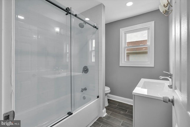 full bathroom featuring toilet, combined bath / shower with glass door, and vanity