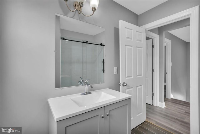 bathroom with a shower with shower door, hardwood / wood-style floors, and vanity