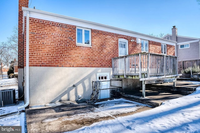 snow covered back of property with a wooden deck and central air condition unit