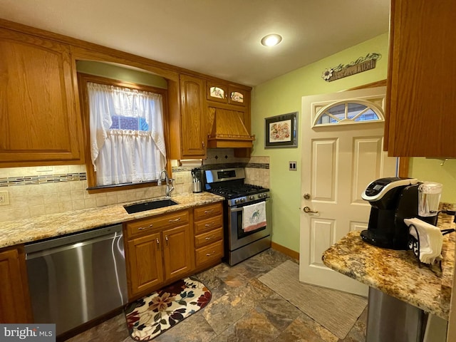 kitchen featuring sink, stainless steel appliances, light stone countertops, custom range hood, and decorative backsplash