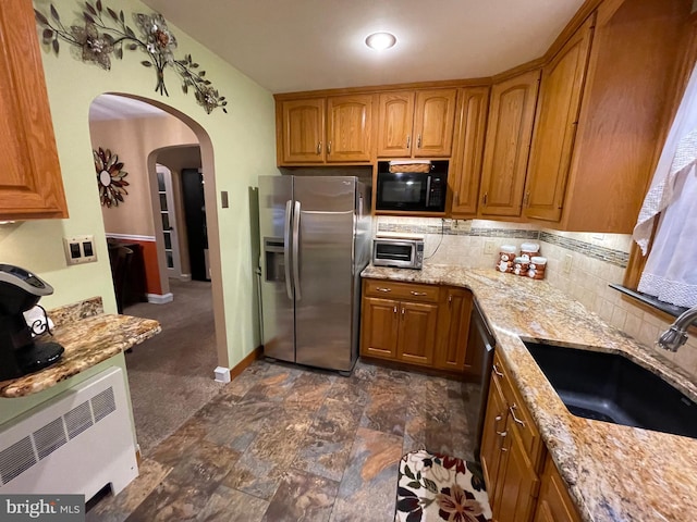 kitchen with sink, dark carpet, stainless steel fridge, and light stone countertops