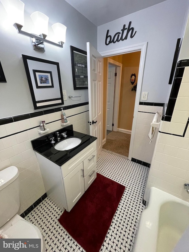 bathroom with vanity, toilet, a bathing tub, and tile walls