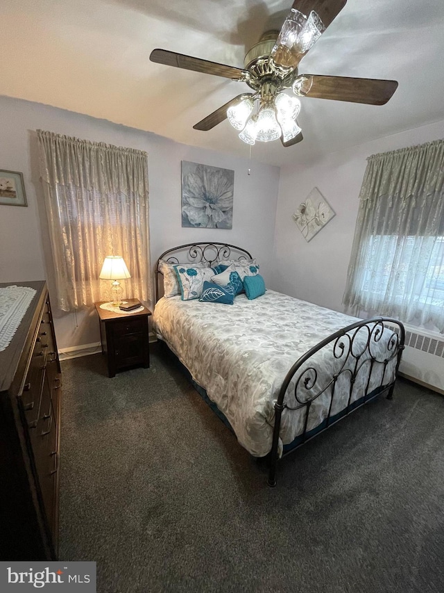 bedroom featuring dark colored carpet, radiator heating unit, and ceiling fan