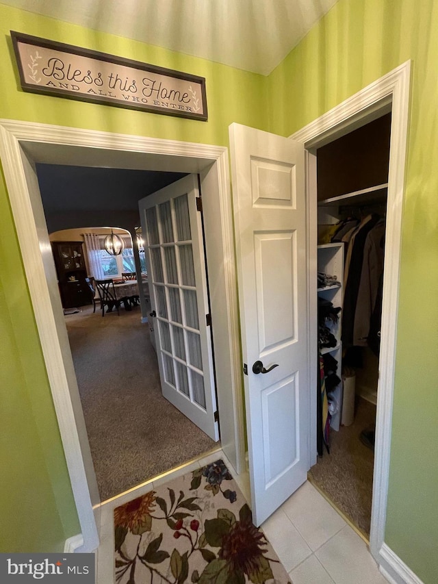 hallway featuring an inviting chandelier and light carpet