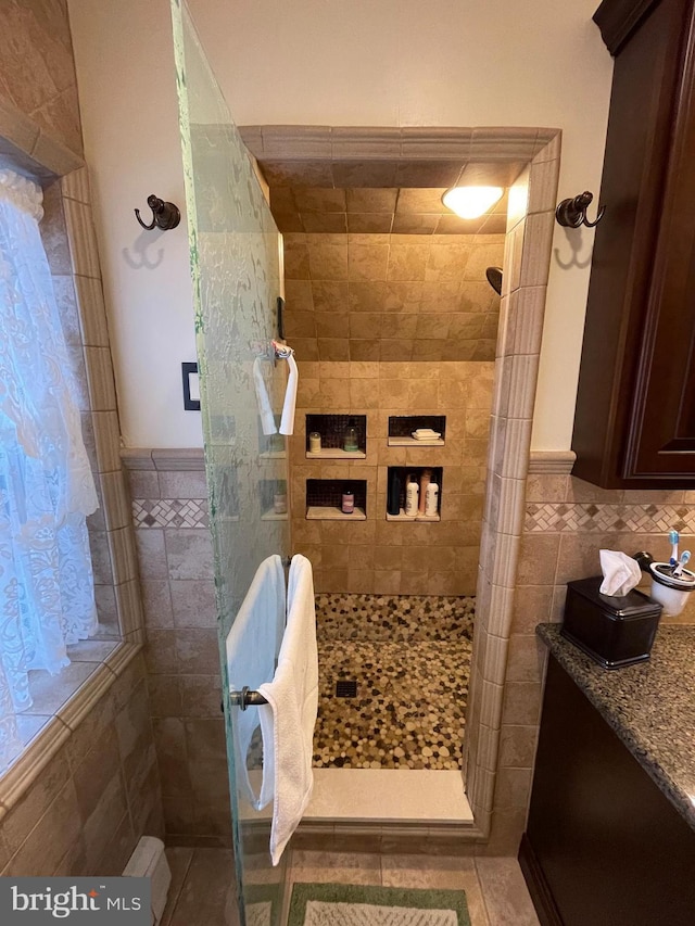 bathroom featuring tiled shower, tile patterned flooring, and tile walls