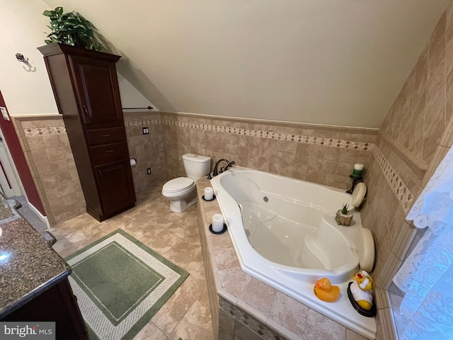 bathroom with tile walls, tiled tub, vanity, and toilet