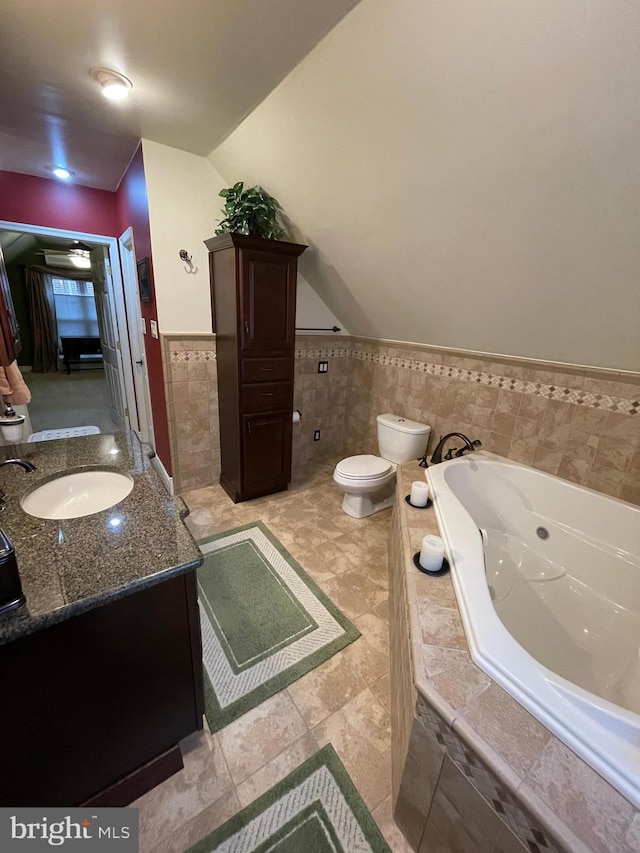 bathroom featuring toilet, vaulted ceiling, tile walls, vanity, and a relaxing tiled tub