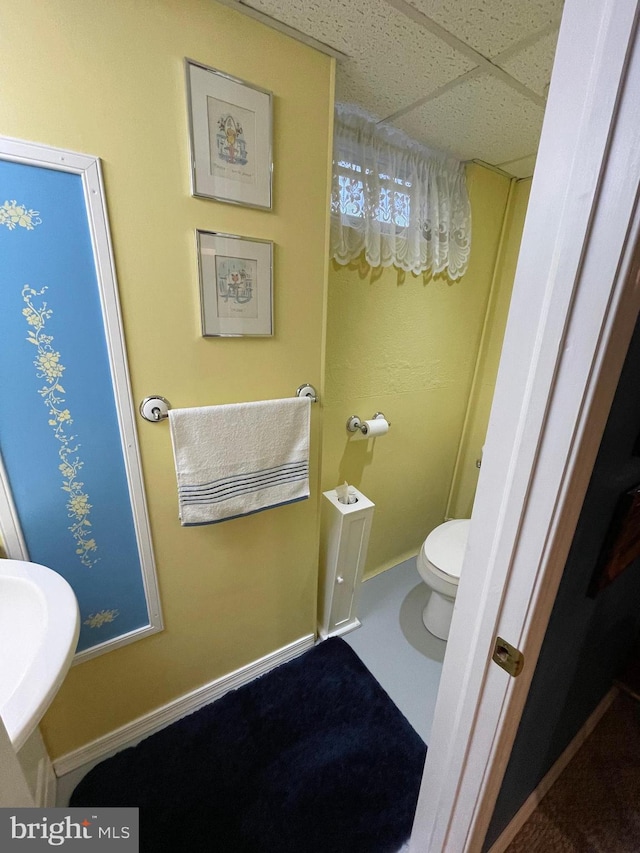 bathroom with sink, a paneled ceiling, and toilet