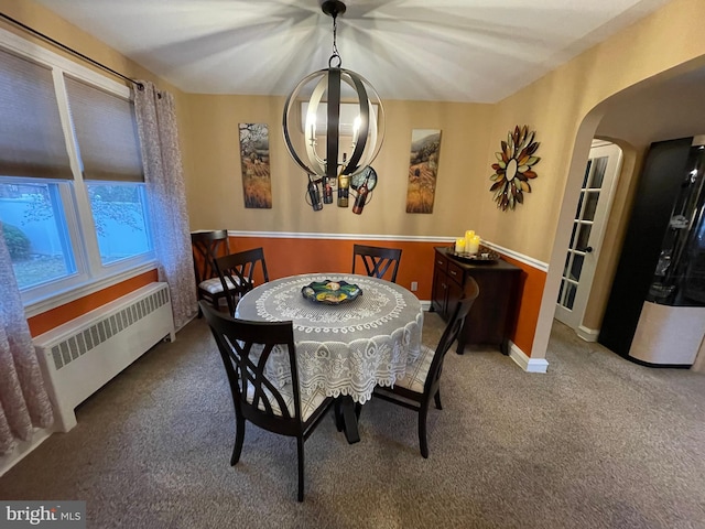 dining room with carpet flooring, radiator heating unit, and a notable chandelier