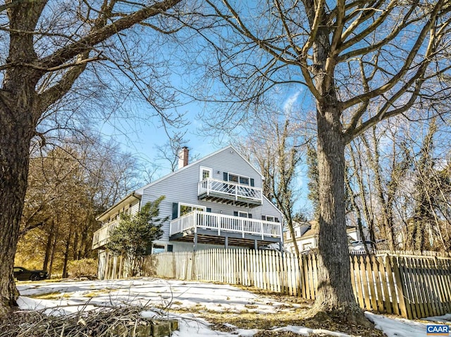 snow covered back of property featuring a balcony