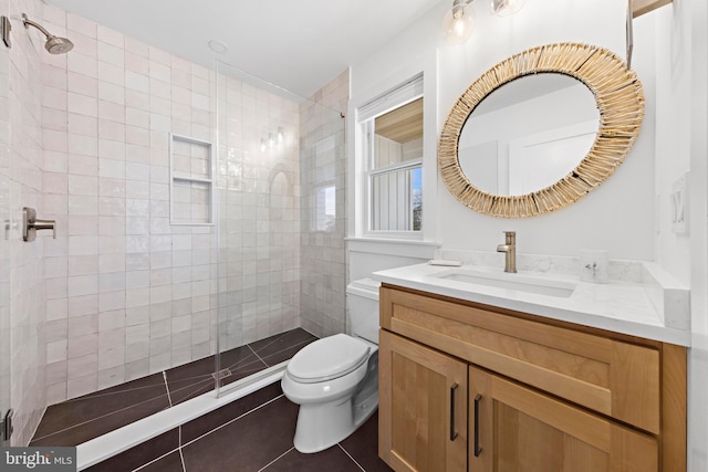 bathroom featuring vanity, tile patterned floors, toilet, and tiled shower