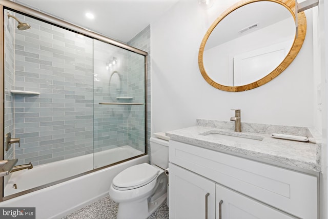 full bathroom with enclosed tub / shower combo, vanity, and toilet