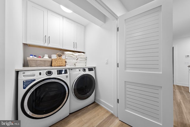 clothes washing area with cabinets, washing machine and clothes dryer, and light hardwood / wood-style floors