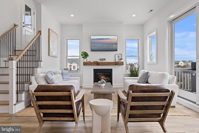 living room with a large fireplace and light hardwood / wood-style floors