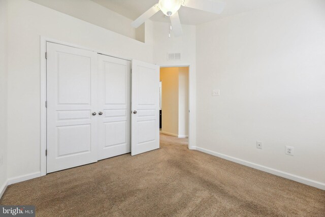 unfurnished bedroom featuring ceiling fan, a closet, and light carpet