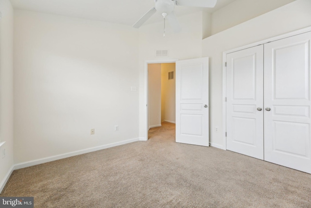 unfurnished bedroom with ceiling fan, a closet, and light carpet