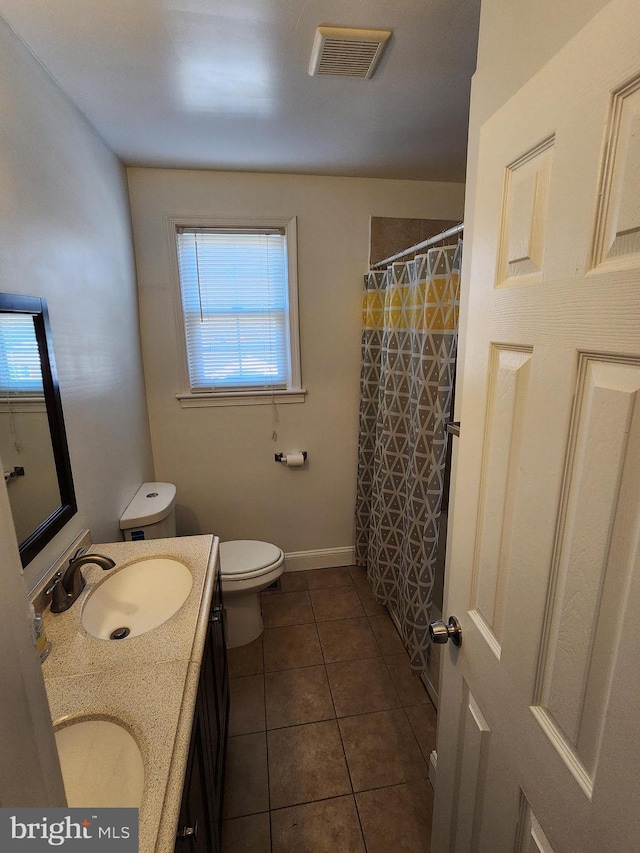 bathroom with toilet, vanity, walk in shower, and tile patterned flooring