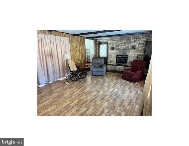 living room with hardwood / wood-style floors, a fireplace, beamed ceiling, and wood walls