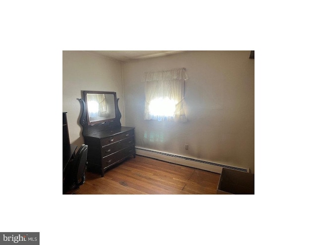 bedroom with wood-type flooring and baseboard heating