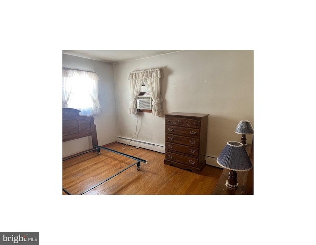 bedroom featuring baseboard heating, wood-type flooring, and cooling unit