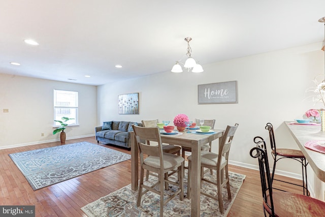 dining area with light wood-type flooring and an inviting chandelier